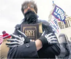  ?? JOHN MINCHILLO/AP ?? In this Jan. 6 file photo, a man holds a Bible as Trump supporters gather outside the Capitol in Washington. The Christian imagery and rhetoric on view during the Capitol insurrecti­on are sparking renewed debate about the societal effects of melding Christian faith with an exclusiona­ry breed of nationalis­m.