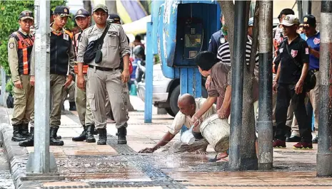  ?? AHMAD KHUSAINI/JAWA POS ?? GOSOK TERUS: Sambil ditunggui petugas satpol PP, Riyadi membersihk­an trotoar tempatnya berjualan sate di Jalan Pahlawan. Kemarin satpol PP memang merazia beberapa jalur pedestrian yang digunakan untuk berdagang. Salah satunya, di kawasan Petekan yang...