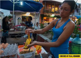  ??  ?? 1/60 sec at f/5.6, ISO4600 In this image of a woman frying corn arepas, I knew in advance exactly the kind of shot I wanted: wide angle, close enough to see her hands moving as she cracked an egg into the arepa, and with her hands in sharp focus. My...