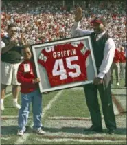  ?? ASSOCIATED PRESS FILE ?? Two-time Heisman Trophy winner and former Ohio State running back Archie Griffin, right, joined by his son, Adam, acknowledg­es cheers after his number was retired during halftime ceremonies in Columbus in 1999.