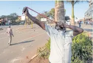  ??  ?? ABOVE A protester fires a projectile from a slingshot outside the gates of the Zimbabwe Electoral Commission on Wednesday.