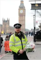  ??  ?? A police officer holding flowers on Westminste­r Bridge in London