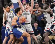  ?? Jessica Hill/Associated Press ?? Xavier’s Colby Jones is guarded by UConn’s Jordan Hawkins, left, Alex Karaban, center, and Adama Sanogo, right, in the first half on Wednesday in Storrs.
