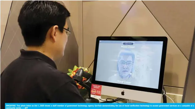  ?? — AFP ?? SINGAPORE: This photo taken on Oct 1, 2020 shows a staff member of government technology agency GovTech demonstrat­ing the use of facial verificati­on technology to access government services on a computer at a community center.