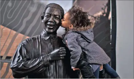  ?? PICTURE: AP ?? A South African girl is held up so she can plant a kiss on the statue of former president Nelson Mandela at the Nelson Mandela Centre of Memory in Johannesbu­rg.