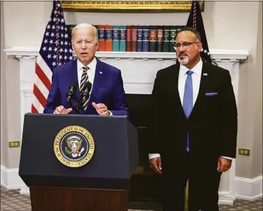  ?? Alex Wong / Getty Images ?? U.S. President Joe Biden, joined by Education Secretary Miguel Cardona, speaks on student loan debt in the Roosevelt Room of the White House in Washington, D.C. , on Wednesday. President Biden announced steps to forgive $10,000 in student loan debt for borrowers who make less than $125,000 per year and cap payments at 5 percent of monthly income.