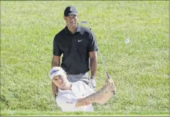  ?? Darron Cummings / Associated Press ?? Justin thomas hits tuesday out of a bunker on the 15th hole as tiger Woods watches during a practice round for the memorial.