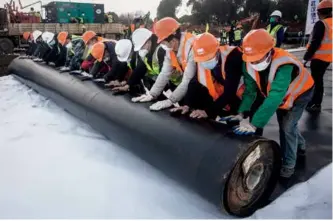  ?? 摄影 无畏 ?? 2020年1月28日，火神山医院建设现场，工人们合力铺设HDP­E防渗膜。HDPE防渗膜具有很­好的防腐性、防渗漏性等性能，可以让污水和废弃物无­法渗透，不污染周边环境。