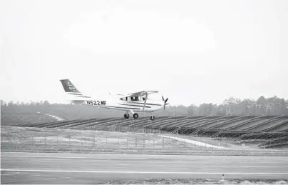  ?? DUSTIN CHAMBERS/THE NEW YORK TIMES ?? A plane gets set to land near solar panels Dec. 5 at Tallahasse­e Internatio­nal Airport in Florida.