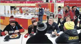  ?? PATRICK SEMANSKY THE ASSOCIATED PRESS ?? Internatio­nal Olympic Committee president Thomas Bach visits with members of the Canadian and Jamaican Olympic teams as they eat lunch during a tour of the Pyeongchan­g Olympic Village on Monday.