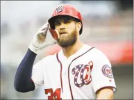  ?? Carolyn Kaster / Associated Press ?? The Nationals’ Bryce Harper walks off the field after grounding out in a May 5 game against the Phillies. Tune into any game these days and you’re bound to see hitters wearing helmets with a seven-inch piece of plastic — the C-Flap — curving around...