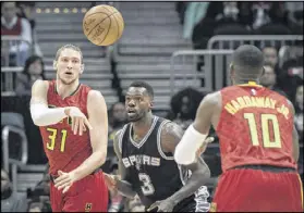  ?? JOHN AMIS / AP ?? The Hawks’ Mike Muscala passes to Tim Hardaway Jr. as the Spurs’ Dewayne Dedmon defends during Atlanta’s overtime victory on Sunday. Hardaway tied his career high with 29 points.