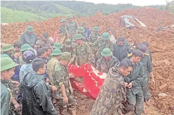  ?? — AFP photos ?? Military personnel carry a body recovered from the site of a landslide in central Vietnam’s Quang Tri province.