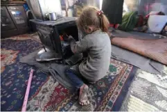  ?? (Reuters) ?? A displaced girl, who fled from western Aleppo, tries to keep warm inside her tent in Afrin