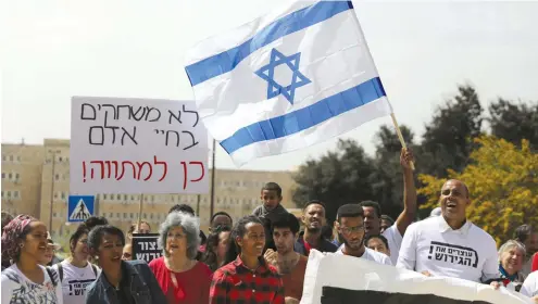  ?? (Reuters) ?? AFRICAN MIGRANTS and Israeli activists demonstrat­e against the planned relocation of thousands of African migrants, outside the Prime Minister’s Office in Jerusalem last month.