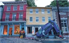  ?? JIM LO SCALZO/ EPA-EFE ?? Rescue workers examine damage on Main Street after a flash flood rushed through the town of Ellicott City, Md., on Sunday.
