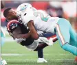  ?? Adam Glanzman / Getty Images ?? Patriots running back Damien Harris is tackled by the Dolphins’ Byron Jones during the first half on Sunday in Foxborough, Mass.