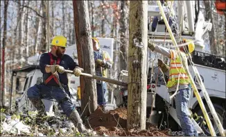  ?? ALYSSA POINTER / AJC ?? Cobb County EMC linemen Jeremiah Gaddis (left) and Stephen Ramsey work to straighten a utility pole into the ground in order to restore power to some in Mountain Park on Monday.