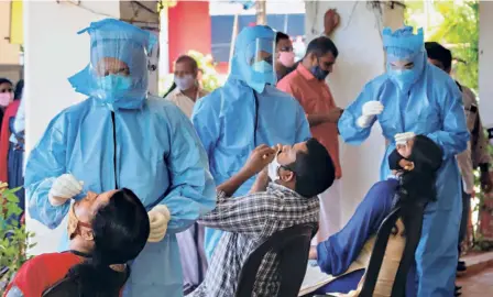  ??  ?? HEALTH WORKERS collect swab samples from corporatio­n employees in Kozhikode on July 21.