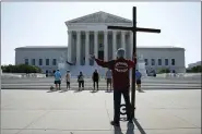  ?? PATRICK SEMANSKY - THE ASSOCIATED PRESS ?? Tom Alexander holds a cross as he prays prior to rulings outside the Supreme Court on Capitol Hill in Washington, Wednesday, July 8. The Supreme Court is siding with two Catholic schools in a ruling that underscore­s that certain employees of religious schools, hospitals and social service centers can’t sue for employment discrimina­tion.