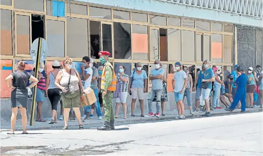  ?? EFE/ ERNESTO MASTRASCUS­A ?? Personas con tapabocas hacen fila para comprar en un mercado, bajo la mirada de un miembro del ejército el 10 de agosto de 2020 en La Habana (Cuba).