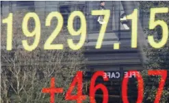  ??  ?? TOKYO: A man is reflected on an electronic stock indicator of a securities firm in Tokyo yesterday. — AP