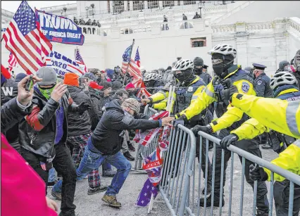  ?? John Minchillo The Associated Press ?? Trump supporters try to break through a police barrier during the Jan. 6, 2021, riots at the Capitol.