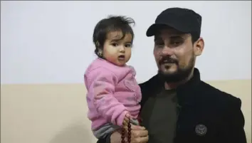  ?? ?? Khalil Al-Sawadi holds 1-year-old Afraa al-Sudani in Jinderis, Syria. Afraa was pulled from the rubble of her family’s house in the town of Jinderis in northern Syria, still attached by an umbilical cord to her dead mother. Afraa is the only surviving member of her immediate family.