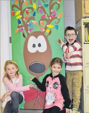  ?? ERIC MCCARTHY/JOURNAL PIONEER ?? St. Louis Elementary School Grades 1 and 2 French Immersion classmates, from left, Alexa Profit, Nelly Bryan and Antwan Peters introduce Rusty the Reindeer, the winning design in the school’s Christmas door decorating contest.