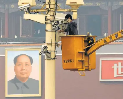  ?? KIM KYUNG-HOON/REUTERS–1/11/2013 ?? Vigilância. Operário conserta câmera na Praça Tiananmen, em Pequim; uigures são principal alvo do governo chinês