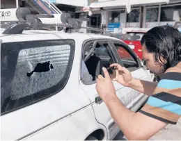  ?? RAHMAT GUL/AP ?? An Afghan journalist films the vehicle Friday in which the director of Afghanista­n’s Government Informatio­n Media Center, Dawa Khan Menapal, was killed in Kabul, Afghanista­n.