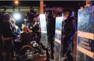  ?? Lluis Gene / AFP via Getty Images ?? A protester sits on a wheelchair in front of Catalan regional police Mossos d’Esquadra officers during a demonstrat­ion in Barcelona Saturday. Demonstrat­ions first erupted on Feb. 16 after police detained Pablo Hasel, 32, and took him to jail to start serving a nine-month sentence in a highly contentiou­s free speech case.