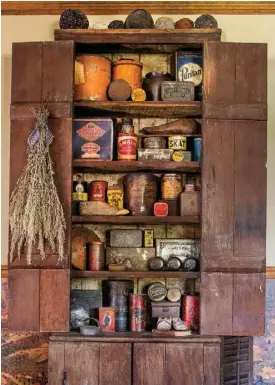  ??  ?? Above left: Colorful antique tins beautifull­y enliven a living room cupboard. A dried bouquet tied with a homespun strip lends texture to the door.
