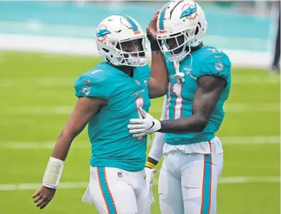  ?? FLORIDA SUN SENTINEL JOHN MCCALL / SOUTH ?? Dolphins QB Tua Tagovailoa and WR DeVante Parker embrace before their game against the Bengals on Dec. 6, 2020.