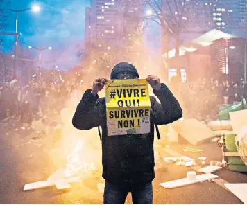  ?? ?? A demonstrat­or holds up a placard reading ‘Live Yes! Survive No!’ during a protest against pension reform in Paris