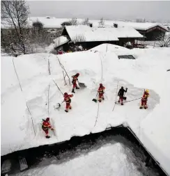  ?? Foto: dpa/DLRG Bayern ?? In Schleching räumen Helfer Schnee von einem Hausdach.