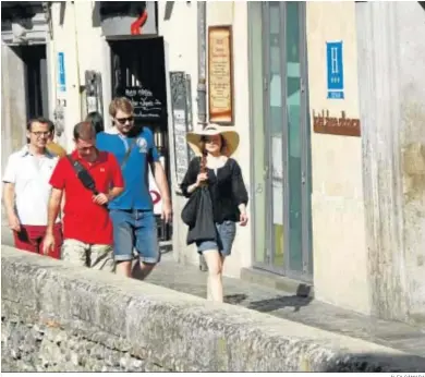  ?? ÁLEX CÁMARA ?? Un grupo de turistas pasea frente a un establecim­iento hotelero, los más perjudicad­os por los pisos de alquiler.