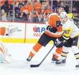  ?? TOM MIHALEK/ASSOCIATED PRESS ?? Pittsburgh Penguins’ Sidney Crosby, right, positions himself in front of the net and Philadelph­ia Flyers’ Ivan Provorov. Crosby led the Pens with four points in a 5-1 win on Sunday.