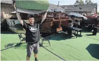  ?? CLIFFORD SKARSTEDT EXAMINER ?? Canoe and Paddle Pub owner Jake Exton hoists a section of AstroTurf being used to create a patio section for the restaurant.