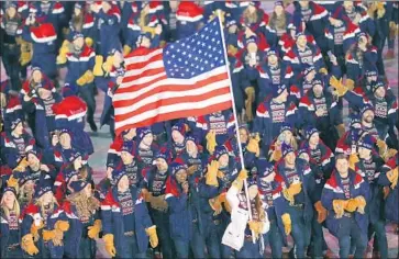  ?? Ronald Martinez Getty Images ?? ERIN HAMLIN CARRIES the f lag for the United States during the opening ceremony, an honor that turned controvers­ial when speedskate­r Shani Davis aired his unhappines­s about the way she was selected.