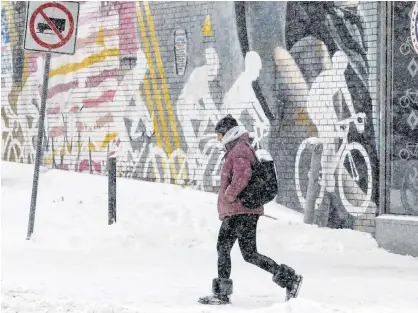  ?? CHRIS HELGREN/REUTERS ?? A woman passes a sporting goods store during a snow storm in Toronto, Ont., Jan. 18.