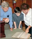  ?? Doug Walker / RN-T ?? Jack Dickey (from left), Liam Mitchell and Jennifer Kearns look at a pre-Civil War ledger book from McGuire’s Store.