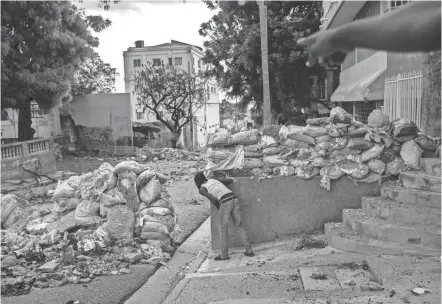  ?? PHOTOS BY RODRIGO ABD/AP ?? A lookout keeps an eye on rival gangsters in downtown Port-au-prince, Haiti. One of the most powerful groups is the G9 coalition of gangs led by Jimmy Cherizier, alias “Barbecue,” whose gang coalition controls the empty streets around the judiciary and legislativ­e buildings, and all streets east to the coast.