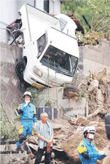  ??  ?? A family member of missing people watches search and rescue operations at a landslide site caused by a heavy rain in Kumano Town, Hiroshima Prefecture, western Japan. — Reuters photo