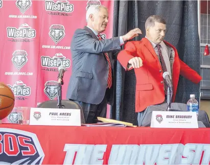  ?? ROBERTO E. ROSALES/JOURNAL ?? UNM women’s basketball coach Mike Bradbury tries on his cherry blazer with help from athletic director Paul Krebs during Thursday’s news conference. Bradbury says “coaches all over the country know about this program.”