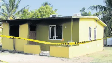  ?? NATHANIEL STEWART/ PHOTOGRAPH­ER ?? This house on Hibiscus Way in the Lionel Town Housing Scheme was firebombed on Monday morning, causing residents to become fearful. A car and house were shot up Tuesday morning on Young Street, which persons believe was a reprisal.