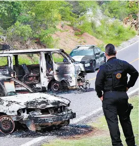  ??  ?? Un federal vigila la zona donde quedaron dos unidades incinerada­s.