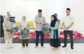  ?? ?? Abang Mohd Shibli (centre) presents the contributi­ons to one of the recipients.