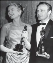  ?? THE ASSOCIATED PRESS ?? In this March 31, 1955, file photo, Grace Kelly, left, and Marlon Brando, hold their best actress and actor Oscars in Los Angeles. Kelly’s icy green satin gown was designed by Edith Head.