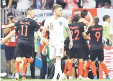  ??  ?? England’s Kieran Trippier reacts as Croatia’s players celebrate their semi-final victory. — AFP photo